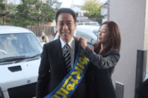 妻・愛里にたすきをつけてもらっている前原誠司