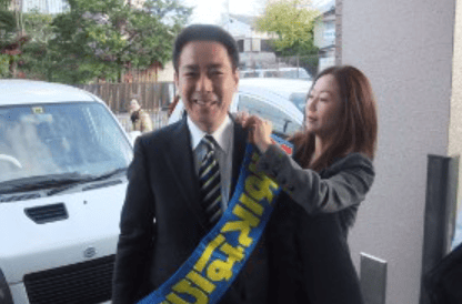 妻・愛里にたすきをつけてもらっている前原誠司